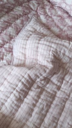 an unmade bed with pink and white bedspread