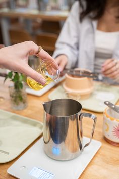 a woman is pouring something into a glass in a pitcher on top of a table