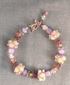 Quaint violet-themed bracelet with hues of pink and purple beads, using different shaped beads and silver beads as spacers and bead caps. This chunky but playful piece is a perfect choice for Mother's Day, Birthday, or any occasion to celebrate your closest friend. Length: 7.5 Inches Closure: Lobster claw ** If you like this adorable bracelet you might also like this one  https://www.etsy.com/listing/611039845/raspberry-parade-simple-purple-and-pink?ref=shop_home_active_2 Purple Drop Earrings, Beautiful Beaded Necklaces, Blue Beaded Bracelets, Diy Jewelry Inspiration, Memorial Bracelet, Jewelry Styles, Blue Beaded Necklace, Purple Beads, Bracelets Design