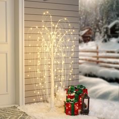 a christmas tree with lights and presents in the snow