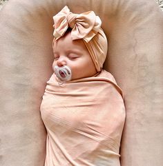 a baby wrapped in a blanket with a pacifier on it's head is sleeping