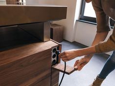 a woman is plugging in an electrical outlet into a cabinet with a power cord