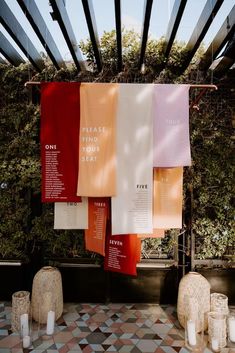 towels hanging from the ceiling in front of some plants and candles on a tiled floor