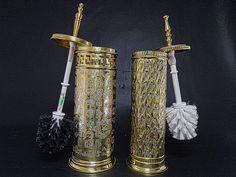 two gold colored vases with brushes in them