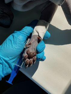 a person in blue gloves is holding something with one hand and an iv attached to the other