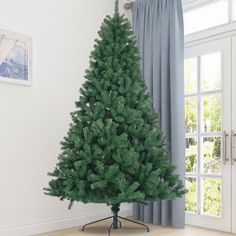 a small green christmas tree sitting on top of a wooden floor next to a window