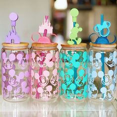 four glass jars with mickey mouse decorations in them