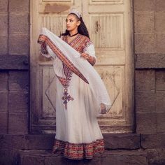 This traditional Ethiopian outfit boasts a full tilf, which is a decorative panel that runs along the bottom of the Habesha Kemis, showcasing intricate patterns and designs. The Habesha Kemis is made from Menen fabric, which is known for its high quality and durability. The Menen fabric is adorned with stunning embroidery, adding to the beauty and elegance of the outfit. The full tilf is the centerpiece of the outfit, featuring a bold and intricate design that commands attention. The colors and Wedding Kaftan With Traditional Patterns, Ceremonial Habesha Kemis With Traditional Patterns, Traditional Patterned Kaftan For Wedding And Transitional Seasons, Traditional Draped Embroidered Kaftan For Festivals, Embroidered Traditional Drape Kaftan For Festivals, Habesha Kemis For Eid With Traditional Patterns, Habesha Kemis For Wedding And Eid With Traditional Patterns, Eid Habesha Kemis For Traditional Ceremonies, Habesha Kemis For Traditional Ceremonies During Eid