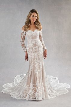 a woman in a wedding dress with long sleeves and an off the shoulder lace top