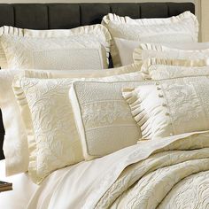 a bed with white comforters and pillows on it