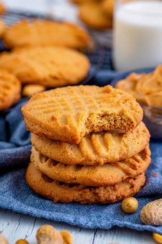 peanut butter cookies stacked on top of each other next to a glass of milk and peanuts