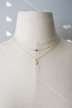 ☞ Features  ✤ Necklaces are each sold separately ✤ ✤ Tiny and dainty cross and Virgin Guadalupe white beaded necklaces. ✤ Choose between the individual necklaces or the set.  ✤ All metal parts of both necklaces are made of 18k gold vermeil material including the virgin oval pendant and cross. The tiny beads are coated with high quality white enamel that will deliver strong durability and shine. ✤ 18K Gold Vermeil - For those with an eye for striking gold, our gold jewelry uses sterling silver as Spiritual Cross Necklace With Beaded Chain, Spiritual Cross-shaped Pearl Chain Jewelry, Delicate Everyday Cross Necklace, Dainty White Cross Necklace, Adjustable Cross Necklace With Delicate Chain, Adjustable Delicate Chain Cross Necklaces, Adjustable Cross Necklaces With Delicate Chain, White Layered Necklace With Adjustable Chain For Gift, White Layered Necklace With Adjustable Chain As Gift