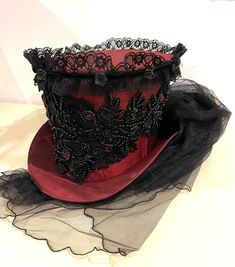 This is elegant Victorian gothic Hand made wine Maroon Top hat with black back beautifully hand crafted feathers and flowers black net bustle train. Top Hat with Black laces and 3D silk flowers and black pearls and dark red jewels and sequins hand stitched.  Please refer to the photos. This is stunning Victorian Steampunk Handmade top hat made with lots of love. It is very well made, this hat is made of a satin type of fabric and the inside of the hat is has a Black satin  lining. The front of t Elegant Halloween Costume Corset, Fitted High Crown Costume Hats And Headpieces, Fitted Steampunk Top Hat For Halloween, Steampunk Fitted Top Hat For Halloween, Steampunk Fitted Mini Hats For Halloween, Fitted Fantasy Hat For Costume Party, Fitted Gothic Costume Accessories For Festivals, Fitted Gothic Festival Costume Accessories, Elegant Red Corset For Costume Party