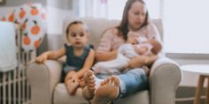 a woman sitting in a chair with two babies