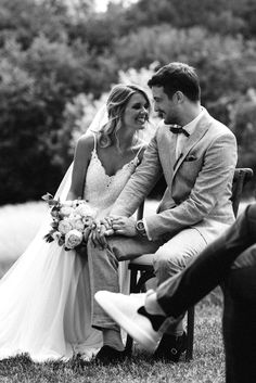 black and white photo of bride and groom sitting on bench at their outdoor wedding ceremony