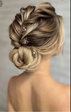 a woman with blonde hair styled into a low bun, wearing two gold bobby clips