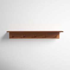 a wooden shelf mounted to the wall with three hooks on each side and an empty white wall behind it