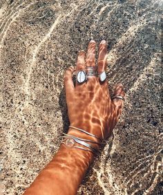 a person's hand in the water with rings on their wrist and bracelets