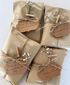 four wrapped gift bags tied with twine and string, each containing a small white flower