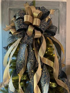 a christmas tree decorated with gold and blue ribbons