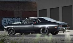 an old car parked in front of a building with graffiti on the wall behind it