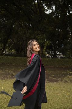 a woman wearing a graduation gown and holding a large black graduate's hat in her hand