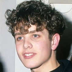 a young man with curly hair wearing a black shirt