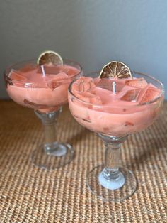 two wine glasses filled with pink liquid and garnished with orange slices on the rim