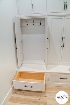 an empty white closet with drawers and hanging hooks