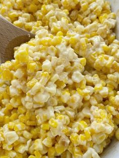 a bowl filled with corn and a wooden spoon