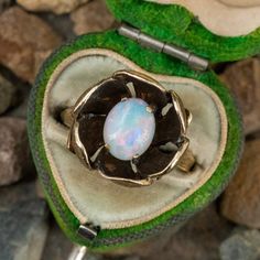 This fantastic vintage opal ring features a 4-prong set, oval cabochon opal at the center of a textured flower. The inside of the flower has been antiqued which really makes the opal pop. The ring is crafted in 14k yellow gold and is currently a size 6.5. This particular opal has a really nice play-of-color in red, green, blue, and violet. Luxury Vintage Oval Cabochon Opal Ring, Heirloom Oval Cabochon Opal Ring, Heirloom Oval Opal Ring Collectible, Elegant Collectible Opal Ring, Antique 14k Gold Opal Ring, Oval Cabochon, Vintage 14k Gold Cabochon Opal Ring, Vintage Opal Cabochon Ring, Victorian Opal Cabochon Ring As Gift, Victorian Cabochon Opal Ring For Gift