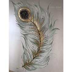 a metal wall hanging with a large feather on it's side and a black dot in the center