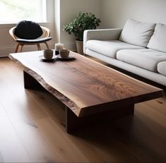 a wooden table sitting in front of a white couch next to a coffee table with two cups on it