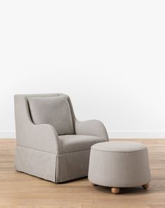 an upholstered chair and footstool in front of a white wall