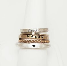 Personalized stackable ring set, engraved with names, a date, or a special word.  Metal: .999 fine silver, 14k gold filled, and 14k rose gold filled Dimensions: Name rings and beaded ring are 2mm tall on average, but our rings are handmade so variations will occur. Birthstone is 2mm on a 1mm band. The silver ring is a chunky organic style and is 3mm. Font: lowercase cursive, uppercase bold block, and lowercase typewriter (if you want a word instead of a heart on the silver ring) Unsure what size Adjustable Stackable Initial Ring, Customizable Adjustable Sterling Silver Engraved Ring, Adjustable Personalized Stackable Rings, Adjustable Customizable Engraved Sterling Silver Ring, Meaningful Customizable Adjustable Rings, Heirloom Style Personalized Everyday Rings, Everyday Adjustable Stackable Engraved Ring, Adjustable Engraved Stackable Ring For Everyday, Meaningful Adjustable Rings With Custom Name