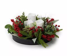 a christmas arrangement with candles and greenery in a black bowl on a white background