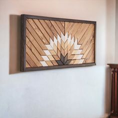 a wooden wall hanging on the side of a white wall next to a brown table