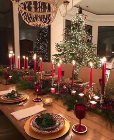 the table is set for christmas dinner with candles on it and plates in front of them