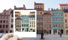 a person holding up a polaroid photo in front of some old buildings on a sunny day