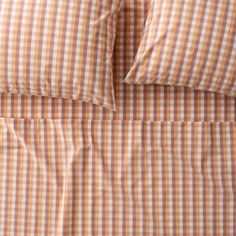 an orange and white checkered comforter set with two pillow cases on top of it