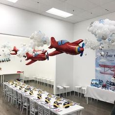 an air plane balloon is being flown over a long table with white tables and chairs