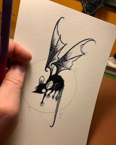 a hand holding a piece of paper with a drawing of a dragon on it