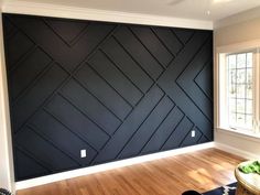 an empty room with wood flooring and black painted wallpaper on the walls, in front of a window