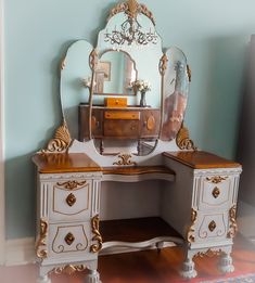 an antique vanity with mirror and drawers in a room that is painted blue, white and gold