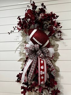 a football wreath hanging on the side of a building with red and white ribbons around it