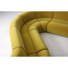 a yellow curved couch sitting on top of a white floor