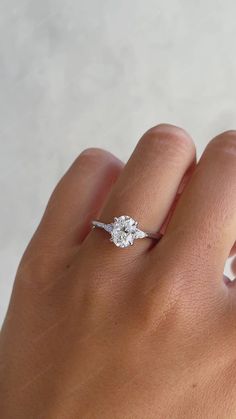 a woman's hand with a diamond ring on top of her left hand,