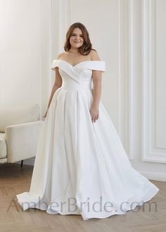 a woman in a white wedding dress posing for the camera with her hands on her hips