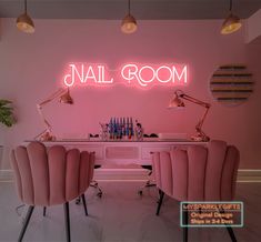 a room with pink chairs and neon lights on the wall above it is an office desk