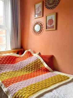 there is a crocheted blanket on the bed next to two pictures hanging on the wall